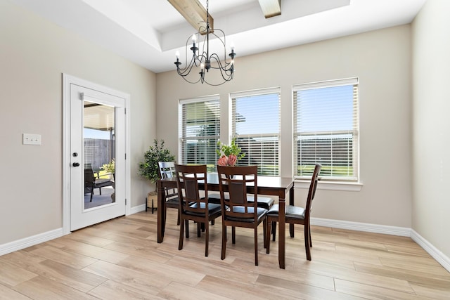 dining room with a notable chandelier, light wood-type flooring, a wealth of natural light, and a tray ceiling