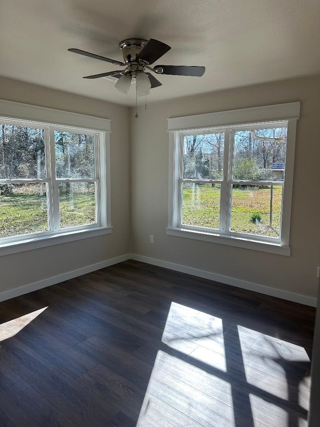 unfurnished room featuring dark wood-style floors, baseboards, and a wealth of natural light