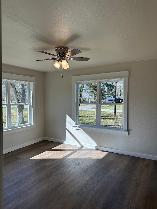 unfurnished room featuring ceiling fan, a textured ceiling, dark wood-type flooring, and baseboards