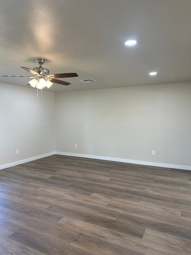 spare room with visible vents, baseboards, dark wood-type flooring, and a ceiling fan