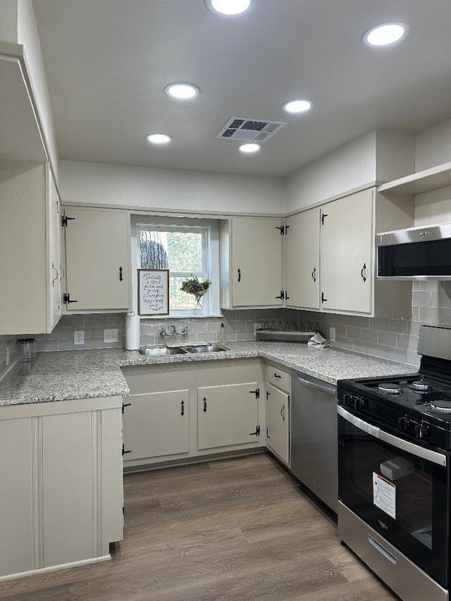 kitchen with visible vents, extractor fan, electric range oven, stainless steel dishwasher, and a sink