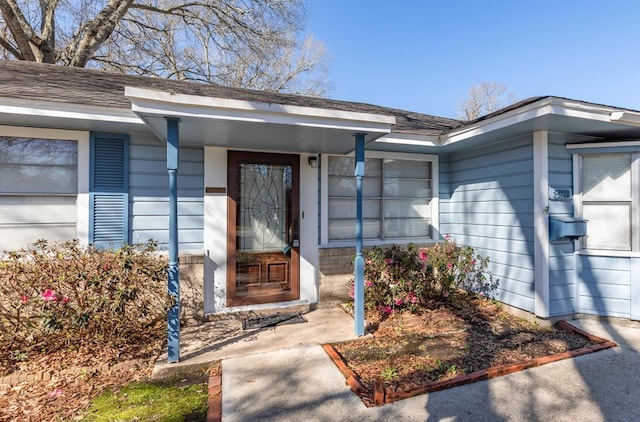 property entrance with a garage and a shingled roof