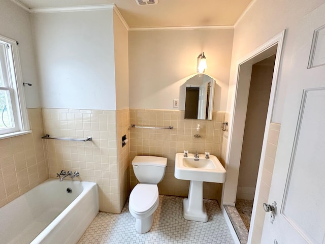 bathroom with tile patterned floors, a bathtub, crown molding, tile walls, and toilet