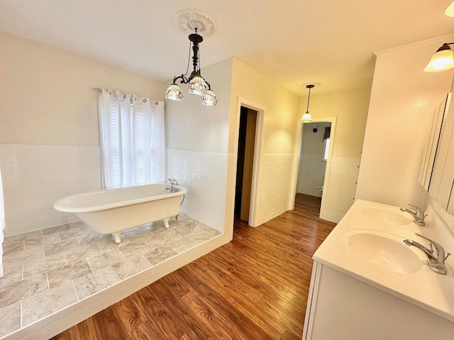 bathroom featuring a washtub, wood-type flooring, tile walls, and vanity