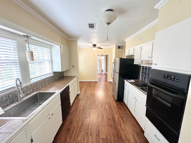 kitchen with sink, hanging light fixtures, decorative backsplash, white cabinets, and black appliances