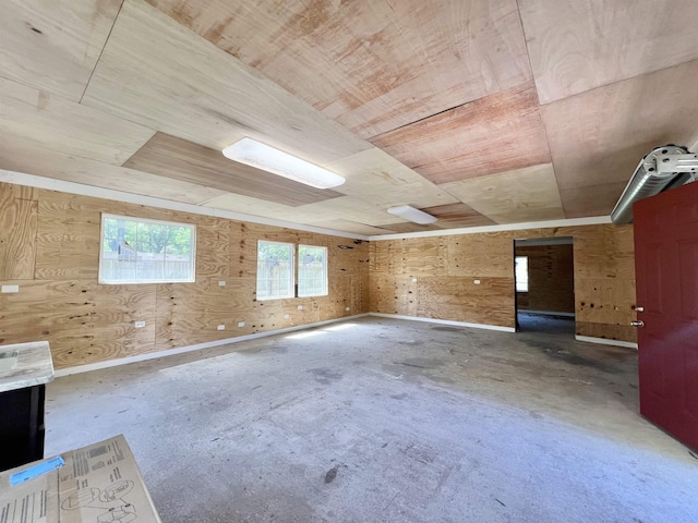 empty room with wood walls, concrete floors, and wooden ceiling