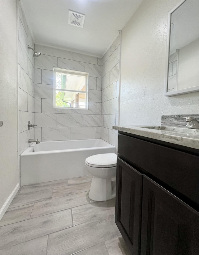 full bathroom featuring vanity, tiled shower / bath combo, and toilet