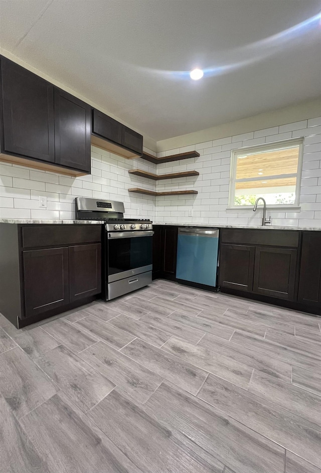 kitchen with dark brown cabinets, sink, light stone countertops, and stainless steel appliances