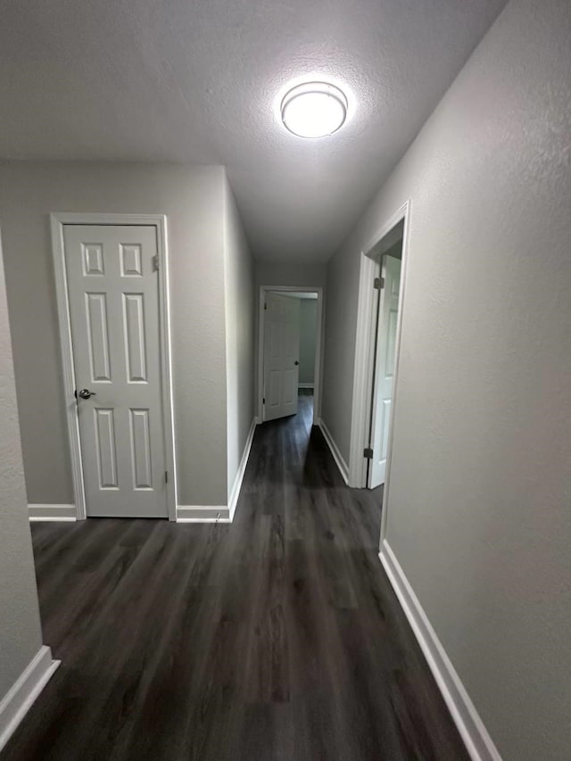 hall with a textured ceiling and dark hardwood / wood-style floors