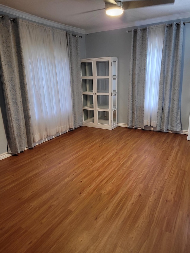 empty room featuring baseboards, wood finished floors, and ornamental molding