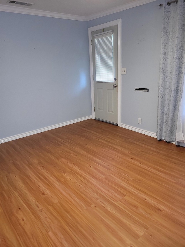 empty room featuring visible vents, light wood-style floors, baseboards, and ornamental molding