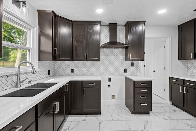 2319 Helena Ave, Nederland, TX 77627 - kitchen featuring wall chimney range hood, a sink, light marble finish floors, tasteful backsplash, and dark brown cabinetry