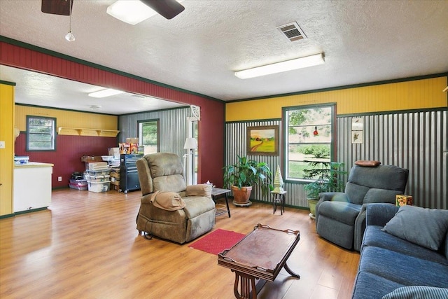 living room featuring crown molding, ceiling fan, a textured ceiling, and hardwood / wood-style flooring