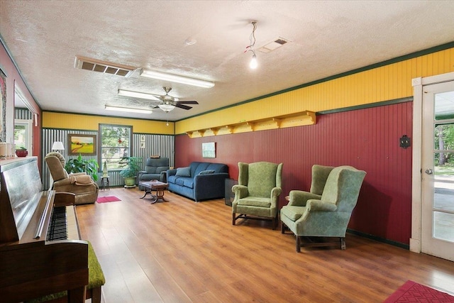 living room with ceiling fan, wood-type flooring, and a textured ceiling