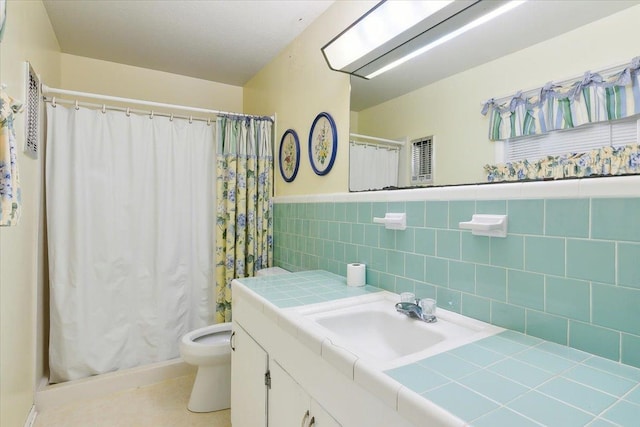 bathroom with vanity, toilet, and tile walls