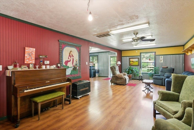 interior space with wood-type flooring, a textured ceiling, ceiling fan, and crown molding