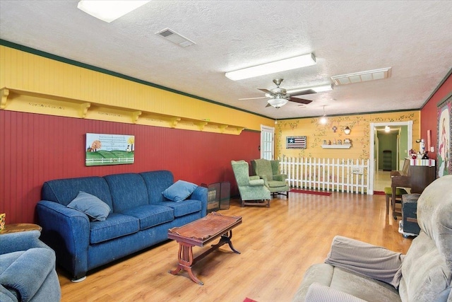 living room with a textured ceiling, hardwood / wood-style flooring, ceiling fan, and ornamental molding