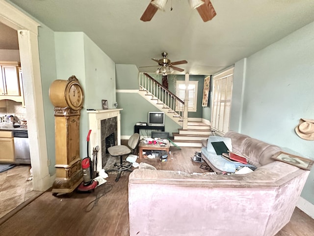 living room with hardwood / wood-style floors, ceiling fan, and a tile fireplace