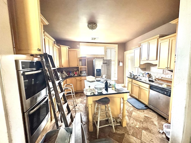 kitchen with a center island, light brown cabinets, a kitchen breakfast bar, decorative backsplash, and stainless steel appliances