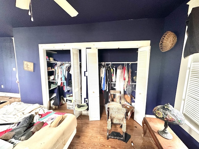 bedroom with hardwood / wood-style floors, ceiling fan, and two closets