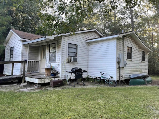 rear view of house featuring cooling unit and a lawn