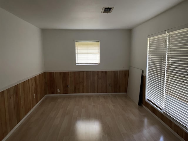 unfurnished room featuring light wood-type flooring and wood walls