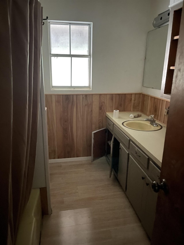 bathroom featuring vanity, hardwood / wood-style floors, shower / bath combo with shower curtain, and wood walls