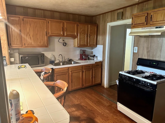 4350 Dallas Ave, Beaumont, TX 77703 - kitchen featuring range with gas stovetop, tile countertops, stainless steel microwave, under cabinet range hood, and dark wood-style flooring