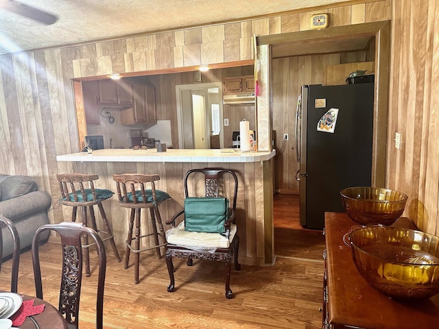 4350 Dallas Ave, Beaumont, TX 77703 - bar featuring freestanding refrigerator, wood walls, under cabinet range hood, wood finished floors, and a textured ceiling