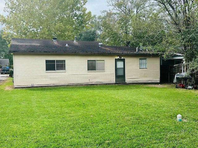 rear view of property featuring a lawn