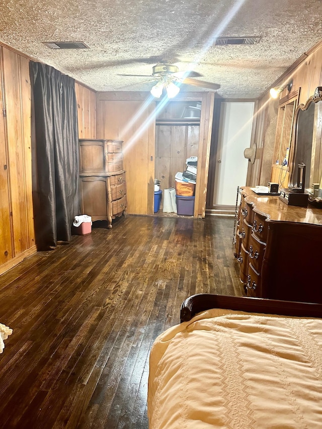 bedroom featuring ceiling fan, dark wood-type flooring, and wooden walls