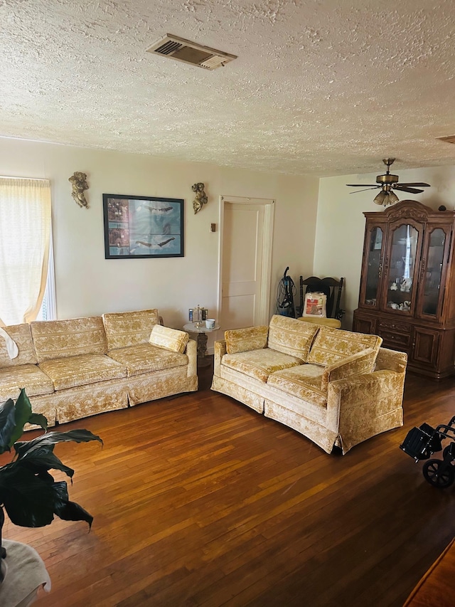 living room with a textured ceiling, dark hardwood / wood-style floors, and ceiling fan