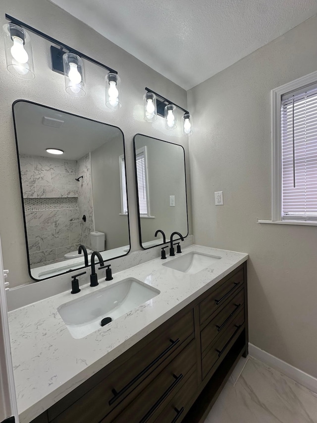 bathroom with vanity, a textured ceiling, toilet, and tiled shower