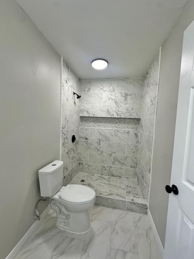 bathroom featuring toilet, a textured ceiling, and a tile shower