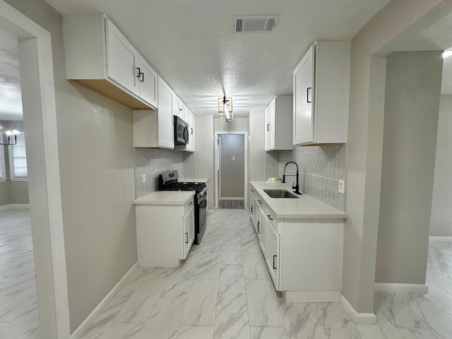 kitchen with sink, white cabinetry, tasteful backsplash, a textured ceiling, and appliances with stainless steel finishes