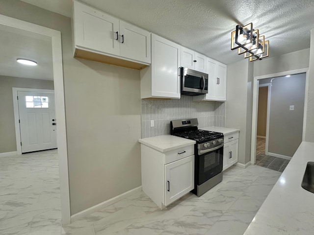 kitchen featuring white cabinetry, decorative backsplash, stainless steel appliances, light stone countertops, and a textured ceiling