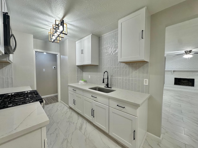 kitchen with sink, a textured ceiling, light stone countertops, and white cabinets