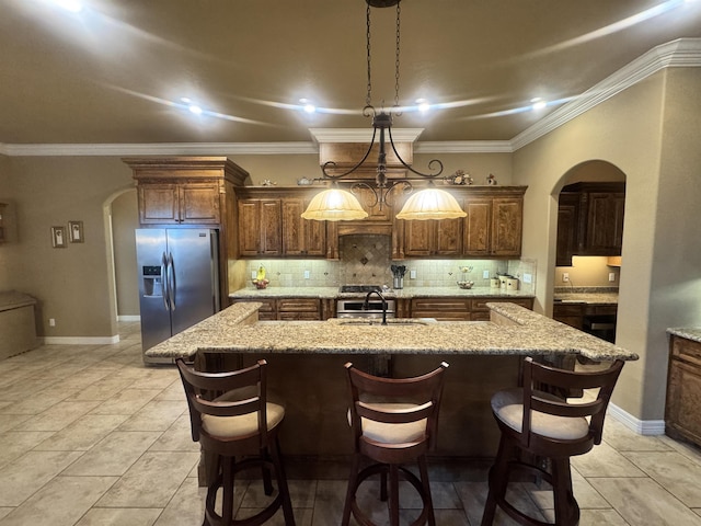 156 Remington Cir, Lumberton, TX 77657 - kitchen featuring stainless steel refrigerator with ice dispenser, arched walkways, a sink, an island with sink, and decorative backsplash