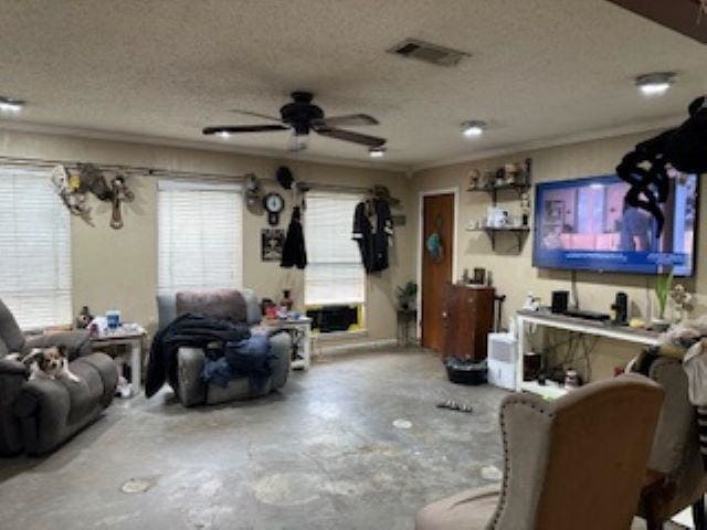 living room with ceiling fan, a healthy amount of sunlight, concrete flooring, and a textured ceiling