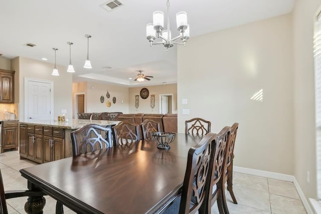 dining space featuring a raised ceiling, ceiling fan with notable chandelier, and light tile patterned floors