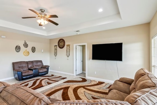 living room with ceiling fan and a tray ceiling