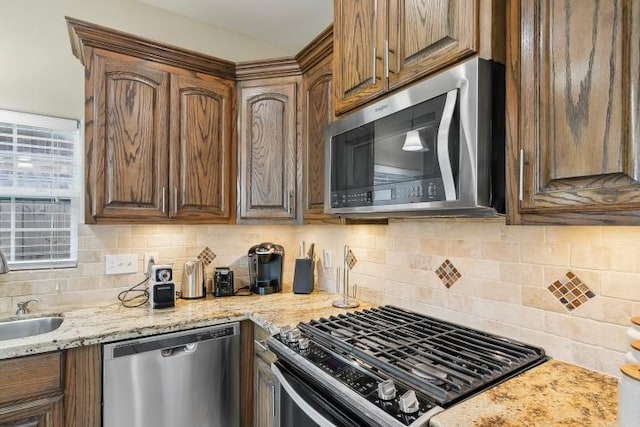 kitchen with stainless steel appliances, sink, light stone counters, and decorative backsplash