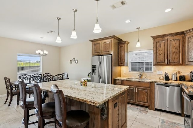 kitchen with a kitchen island, appliances with stainless steel finishes, sink, and pendant lighting