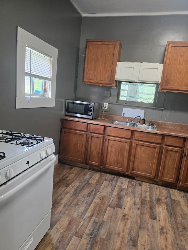 936 9th St, Port Arthur, TX 77640 - kitchen featuring stainless steel microwave, white range with gas stovetop, brown cabinetry, and dark wood finished floors