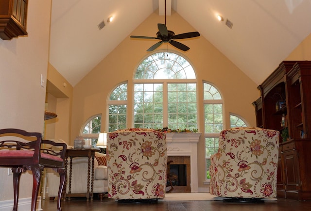 living area featuring ceiling fan, beam ceiling, a tile fireplace, and high vaulted ceiling