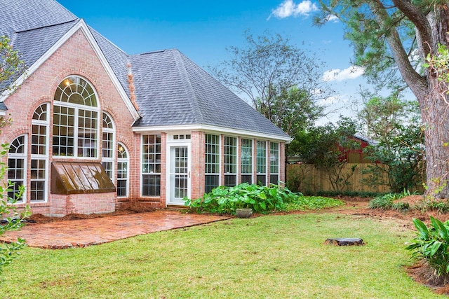 back of house featuring a patio area, a yard, and a sunroom