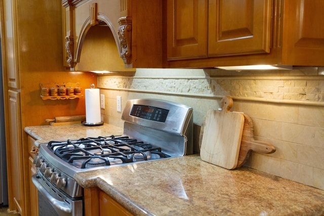 kitchen with stainless steel gas stove and backsplash