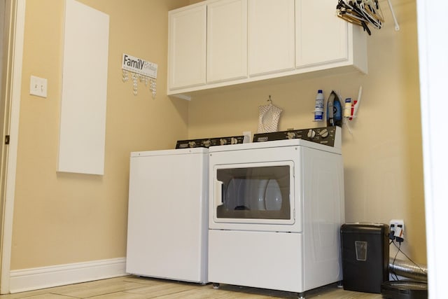 clothes washing area featuring cabinets, washer and clothes dryer, and light hardwood / wood-style flooring