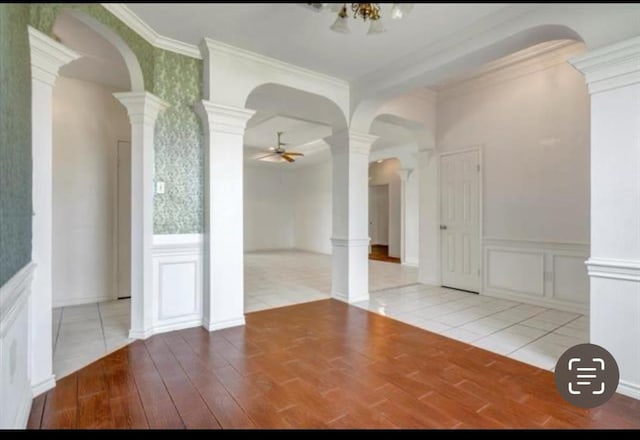 spare room with decorative columns, crown molding, a decorative wall, and a ceiling fan