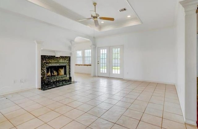 unfurnished living room featuring light tile patterned floors, ceiling fan, visible vents, and a raised ceiling